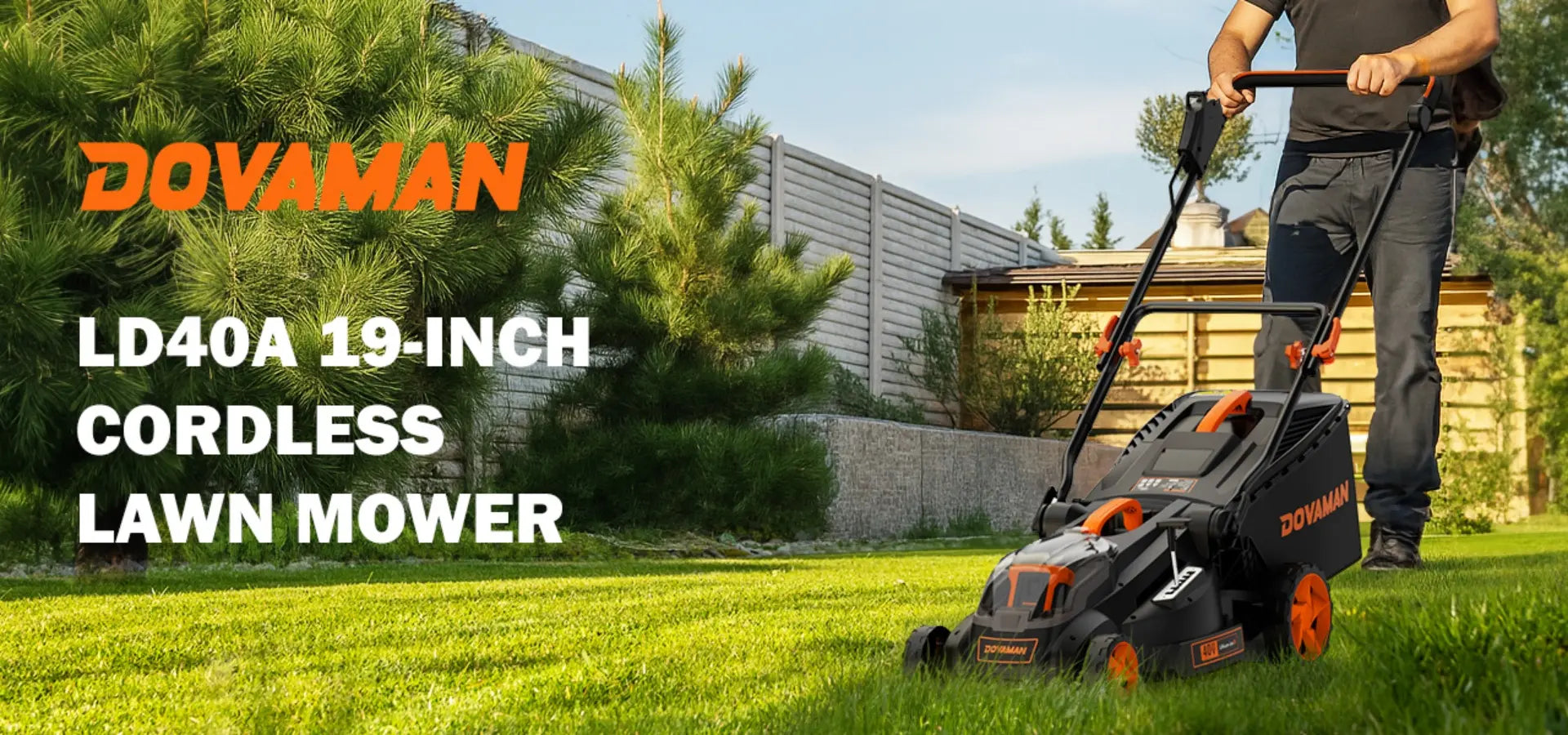 Person using a Dovaman cordless lawn mower on a grassy area with trees and a building in the background.