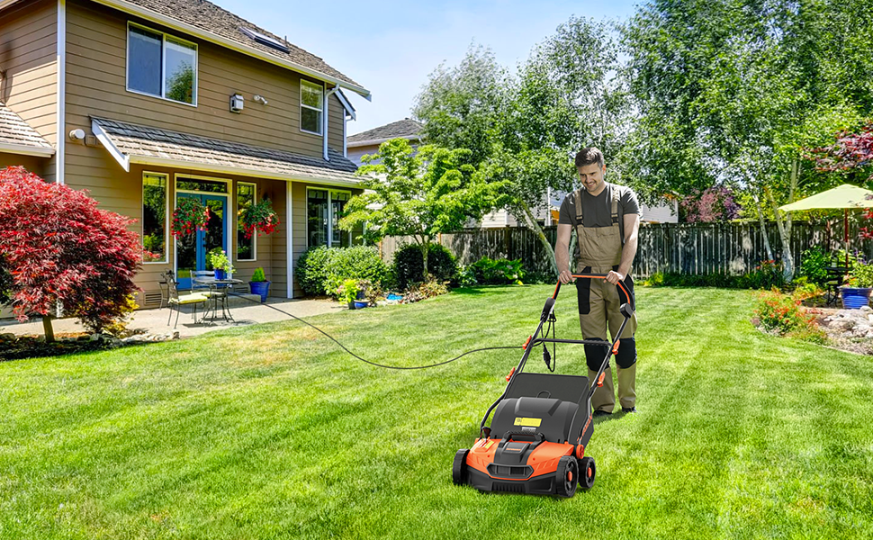 Person using a lawn mower on a green lawn in front of a house with trees and flowers.