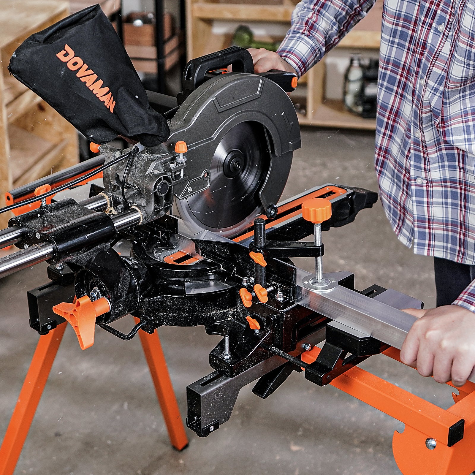 sliding miter saw with orange accents being used by a person in a workshop setting.
